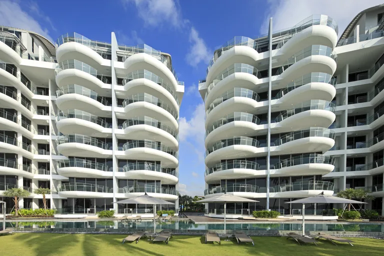 Seascape, photograph: the two curved white blocks at 57 and 59 Cove Way, their balconies swelling outward like the hulls of ships, above the pool deck, loungers and palms under a bright sky